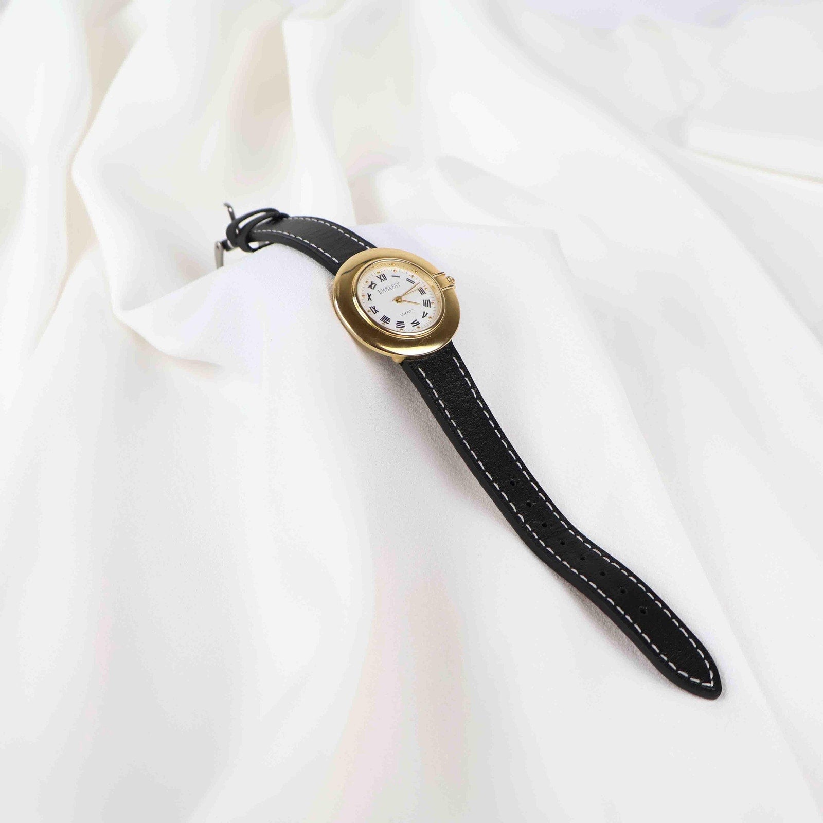 Vintage Embassy Watch with a Gold Round Face and Black Leather Strap