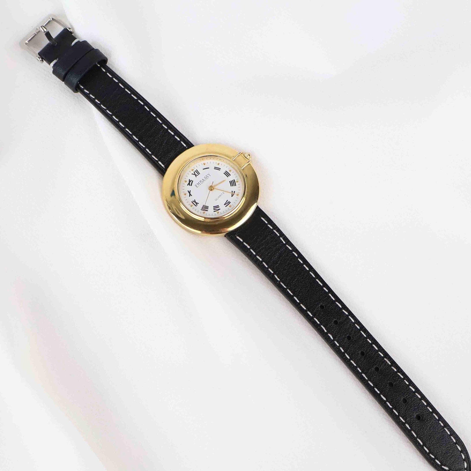 Vintage Embassy Watch with a Gold Round Face and Black Leather Strap